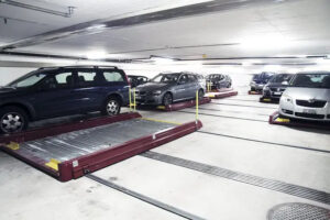 The image shows a Sotefin pallet system. In a pallet system, cars are placed in a metal tray-shaped structure (pallet) to be moved and parked. Unlike palletless systems, here the mechanical device moves the actual pallet transporting the vehicle. These systems are less versatile than carriage-based installations but are a viable option for small car parks.